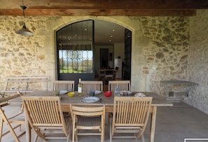Dining table under a shaded terrace opening onto the living room