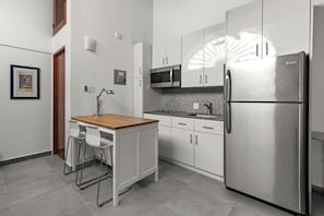 livingroom with kitchen , stainless steel fridge, air conditioner, sofabed, seats, ceiling fan, microwave, reading lamps, cabinets