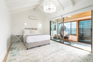 Retreat upstairs to the primary suite, where a queen bed dressed in crisp linen awaits and glass doors open to calming views over the Derwent.