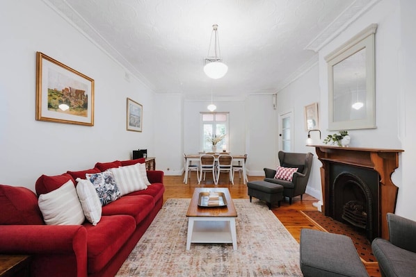 Gather in the main living area, where a three-seater sofa, soft armchairs, and a decorative fireplace create a welcoming area to unwind with a book or share a glass of local wine.