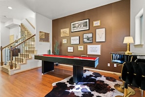The living room features a game table and a mini bar table with seating for two