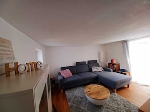 Wohnzimmer mit Terrassentüren zum Garten und TV.