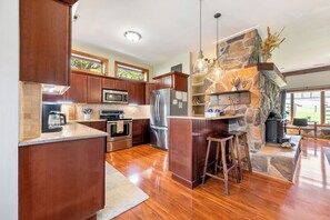 Fully equipped kitchen with bar seating and rustic stone finishes.
