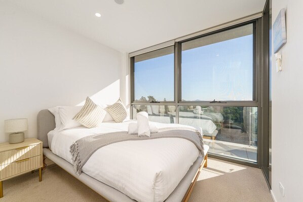 Scandinavian-style bedroom with a queen bed and scenic views of Canberra.