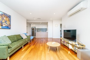 Cosy green sofa, Smart TV, and balcony with stunning Canberra views.