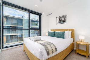 Unwind in a peaceful bedroom featuring a comfy queen-sized bed and a large glass window that lets in plenty of natural light. The perfect spot to rest and recharge after a day out.