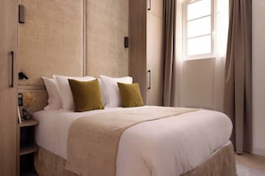 Une chambre parée d’un lit Queen size, d'une penderie, d'une TV et sa salle d'eau attenante équipée d'une douche et d'un lavabo.
