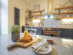 Dining table with plates and cutley on top in the kitchen.