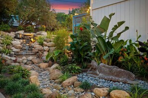 Tranquil garden featuring a water fall and buddha statues.