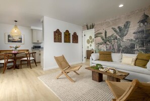Bright open layout living room and dining room. Wallpaper mural with stylish teak furniture and authentic decorations from Bali.