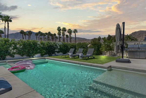 Stunning pool and spa with mountain views at sunset.