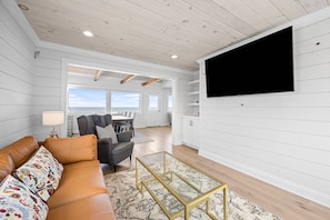 Another view of the living room with flatscreen smart TV and dining area with ocean views