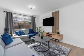 Chic and spacious living room with modern decor, a smart TV, and a cozy corner sofa—perfect for unwinding in style.
