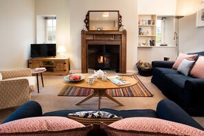 The Bothy at Cheswick - cosy sitting room with seating positioned in front of the wood burner