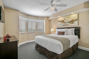 Retreat to this cozy bedroom featuring a king-size bed, equipped with modern comforts and natural light from large windows for a serene escape.