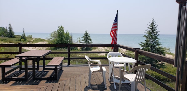 Expansive deck with picnic seating and lounge chairs, ideal for outdoor dining or soaking in Lake Michigan views.