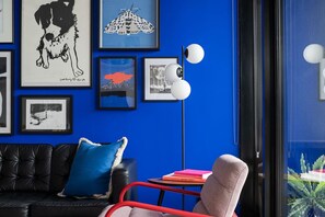 Unwind in this bold and artistic living space, featuring a gallery wall, modern lighting, and vibrant pops of color that make a lasting impression