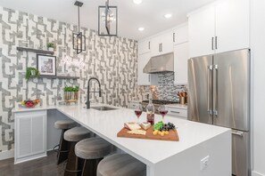 2nd Floor: Sleek and stylish kitchen boasting a bold accent wall, gleaming countertops, and stainless appliances.