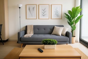 Relax in this stylish living room, featuring a cozy sofa, modern decor, and a touch of greenery for a refreshing ambiance.