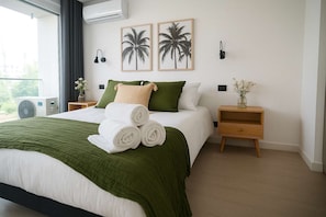 Relax in this stylish bedroom featuring a cozy king-sized bed, modern decor, and abundant natural light for a refreshing stay.