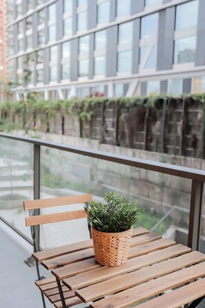 Relax on the cozy patio with a refreshing view of modern architecture and lush greenery, perfect for morning coffee or evening unwinding.