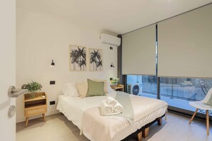 Relax in this serene bedroom with modern decor, plush bedding, and a private balcony view. Perfect for unwinding after a day of exploring.
