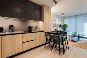 Experience modern living in this stylish kitchen, featuring sleek cabinetry and a cozy dining area perfect for meals and gatherings.