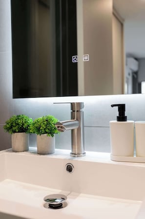Experience modern elegance in this stylish bathroom featuring a sleek sink, chic decor, and ambient lighting.