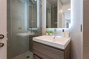 Experience a sleek and modern bathroom with a spacious shower and stylish decor, perfect for a refreshing retreat during your stay.