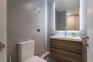 Experience a sleek and modern bathroom with stylish finishes and a touch of greenery for a refreshing stay.