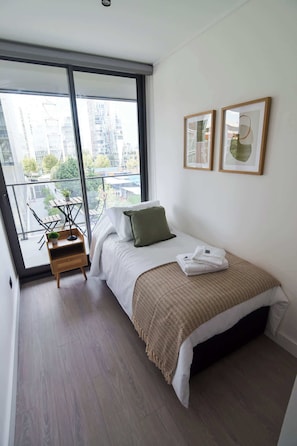 Cozy bedroom with city views, modern decor, and a relaxing balcony. Perfect for your urban getaway!