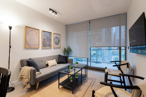 Relax in this chic living room with a modern sofa, stylish decor, and a view of the city skyline through expansive windows.