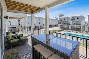 Covered porch overlooking pool with table and loungers