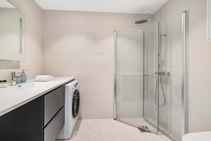 A well-appointed rental bathroom, featuring a spacious shower and a built-in washing machine.