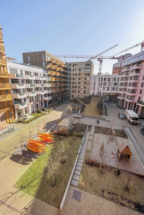 Spacious courtyard with a mix of paved areas, grassy spaces, and a children's play area.