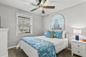 The third bedroom features a queen bed, a TV, and calming blue accents, creating a serene and cozy retreat.