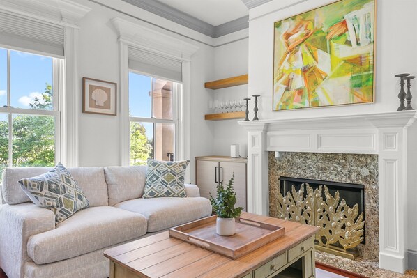 Sunlight pours through the large windows, filling this cozy living space with warmth and charm—perfect for morning coffee, afternoon lounging, or unwinding with a favorite show.