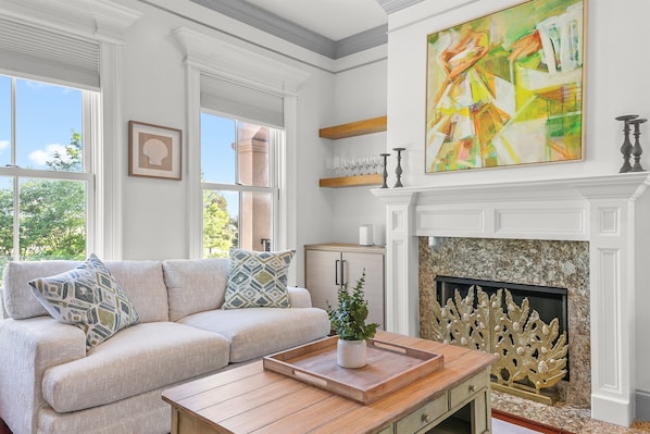 Sunlight pours through the large windows, filling this cozy living space with warmth and charm—perfect for morning coffee, afternoon lounging, or unwinding with a favorite show.