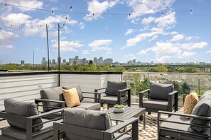 Private rooftop deck with hot tub, outdoor seating, bistro lighting, and stunning city skyline views. (4th Floor)