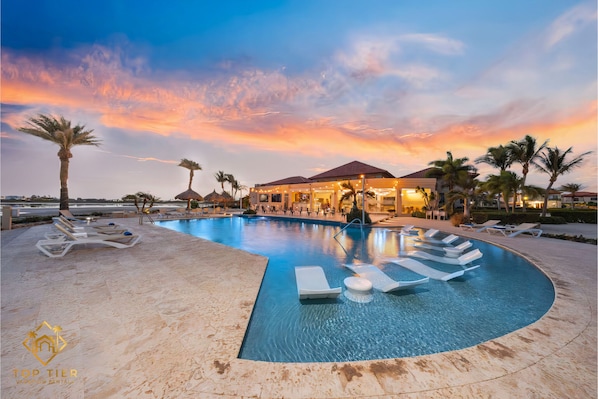 Resort-style infinity pool with in-water loungers and palm-lined views.