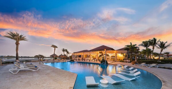 Resort-style infinity pool with in-water loungers and palm-lined views.