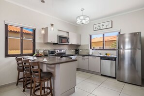 Fully equipped kitchen with modern appliances, bar seating & natural light.