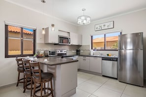 Fully equipped kitchen with modern appliances, bar seating & natural light.