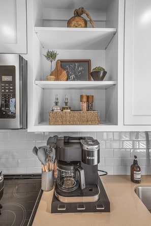 Start your mornings right with our fully stocked Keurig coffee bar, nestled below open shelving with thoughtfully curated décor and essentials.