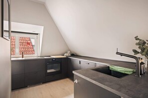 A modern, dark-toned kitchen with a sloped ceiling, perfect for a cozy atmosphere.