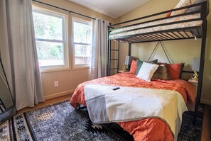 Rest easy in the queen-size bed, adorned with vibrant patterns and warm earthy tones. Above, a lofted twin bed adds a unique touch to accommodate an extra guest or create a cozy nook for relaxation. 