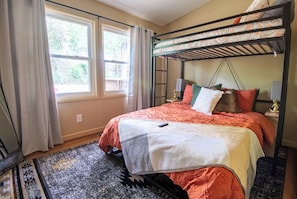 Rest easy in the queen-size bed, adorned with vibrant patterns and warm earthy tones. Above, a lofted twin bed adds a unique touch to accommodate an extra guest or create a cozy nook for relaxation.