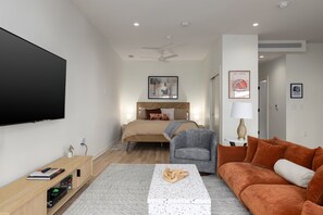 Serene and stylish—this cozy bedroom features a comfortable bed with warm, neutral tones, modern art, and a ceiling fan for a peaceful night’s rest.