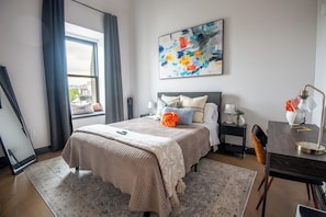 Experience a refreshing wake-up in our vibrant bedroom featuring a cozy queen bed, full of color and life, complemented by a full-length mirror to start your day right.