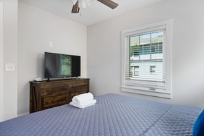 Cozy and inviting, this bedroom showcases a comfortable bed, serene color palette, and a view of the neighborhood through charming windows.